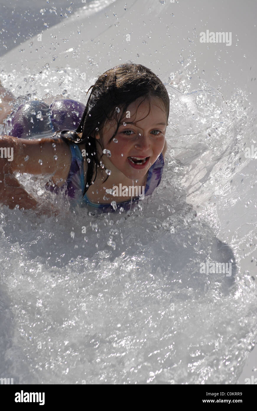 Little girl sliding head first down a water slide Stock Photo