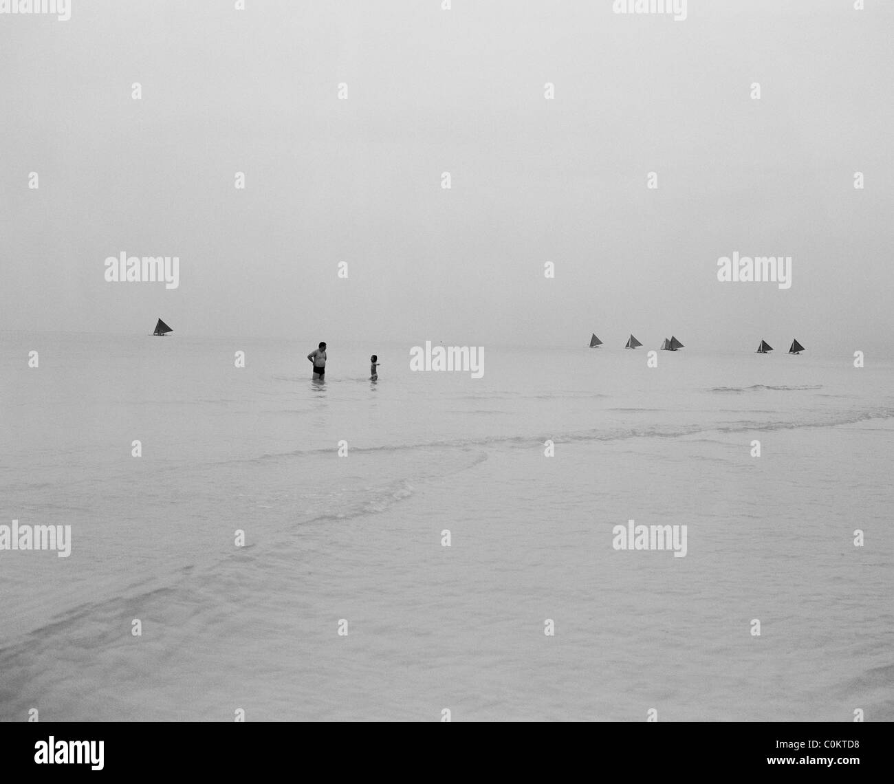 Asian tourists in the ocean on a gloomy morning at White Beach, Boracay Island, the Philippines. Stock Photo