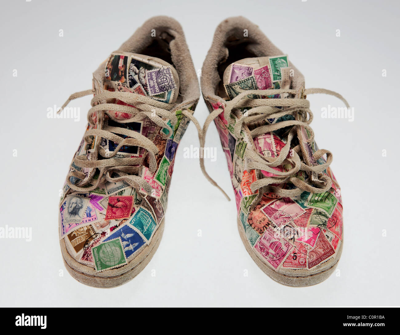 a pair of worn running shoes covered with old postage stamps on a clear