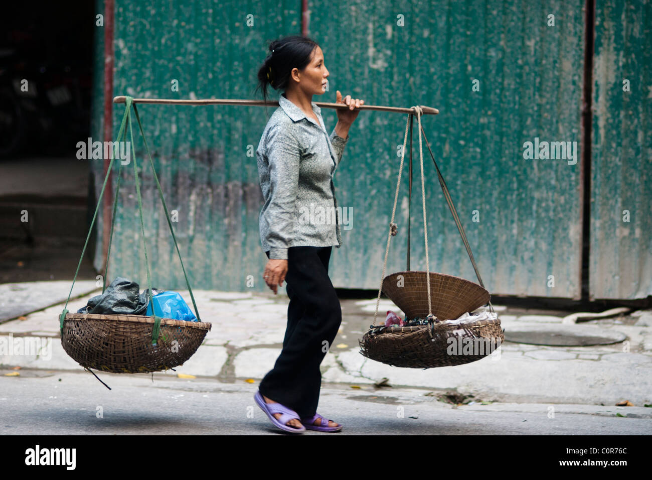 Vietnamese woman caring rubbish in the baskets on a way back from the market Stock Photo