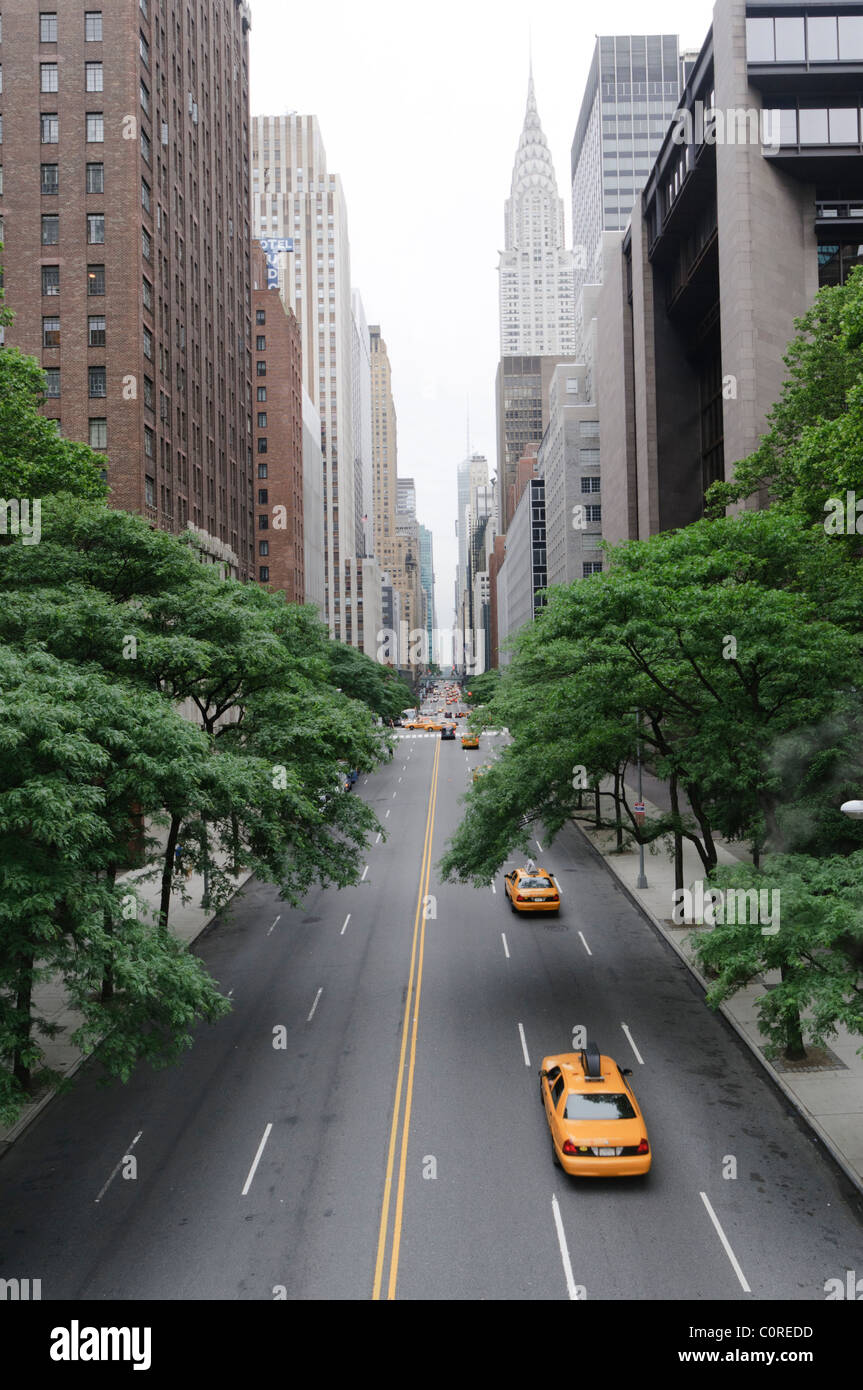 New York Taxis driving up a road with the Chrysler Building in the skyline Stock Photo