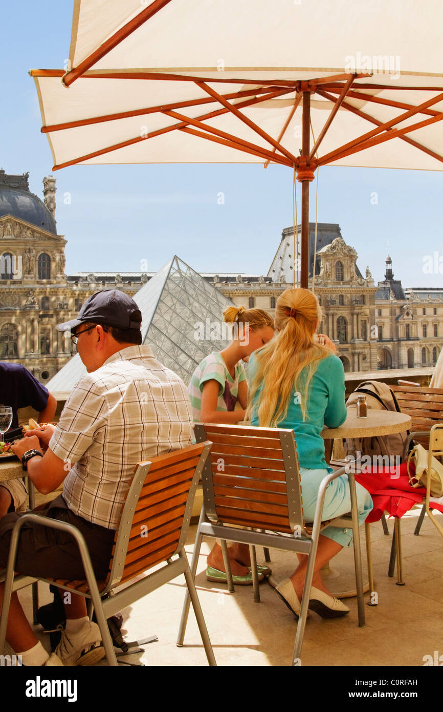 Tourists at a sidewalk cafe near a pyramid, Louvre Pyramid, Musee Du Louvre, Paris, France Stock Photo