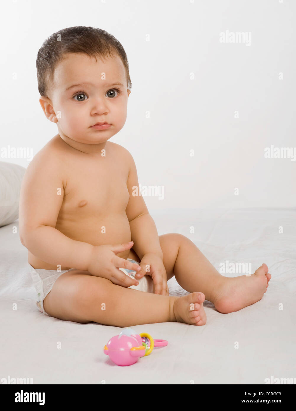 Baby boy playing with a rattle on the bed Stock Photo