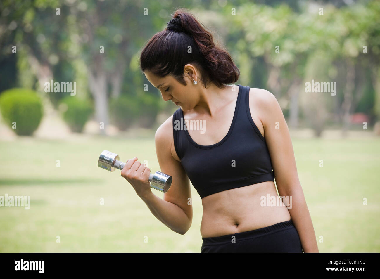 Woman exercising with a dumbbell in a park Stock Photo