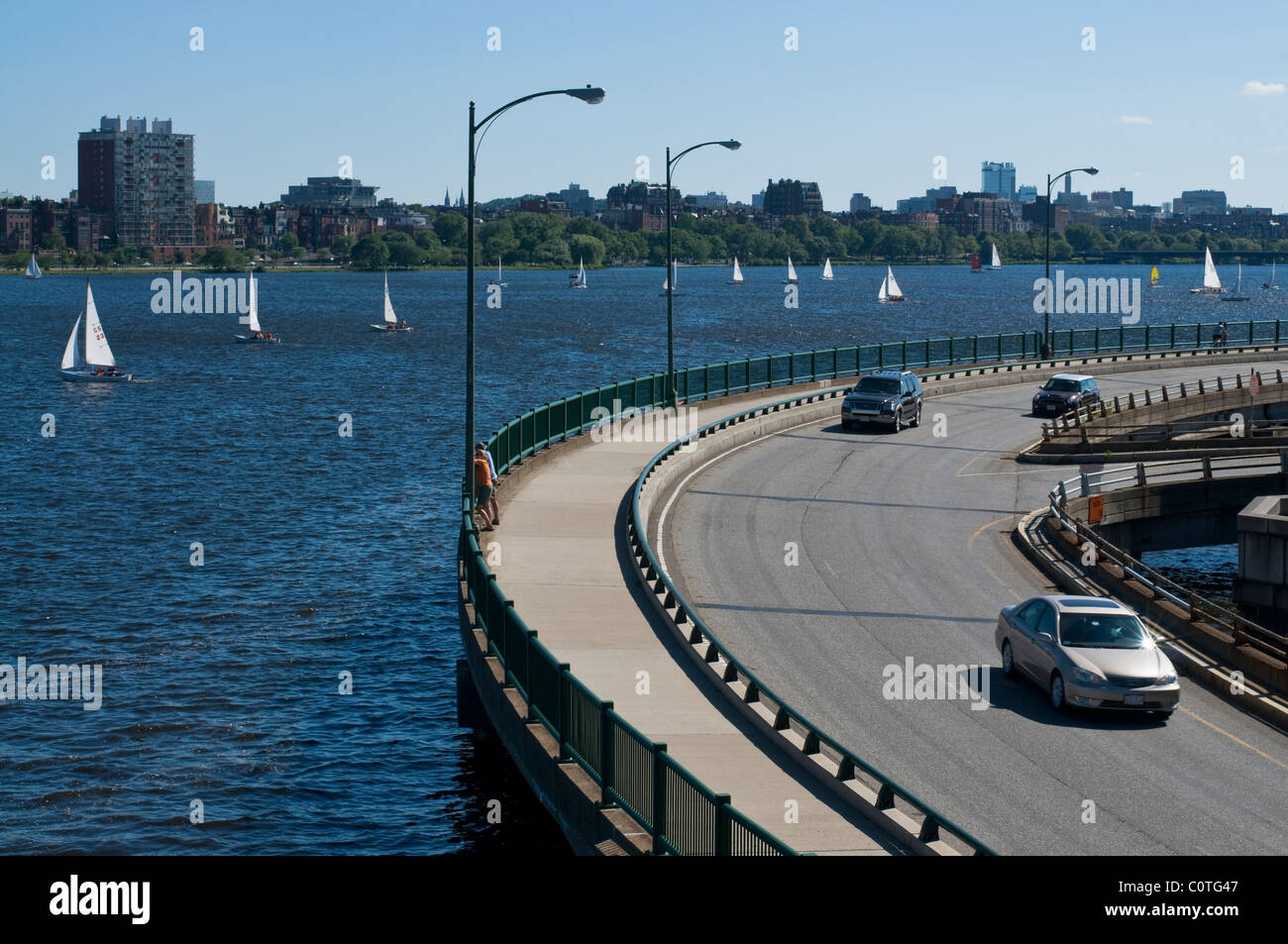 A stretch of road in Boston MA. on the Charles river with sail boats in the background. Stock Photo
