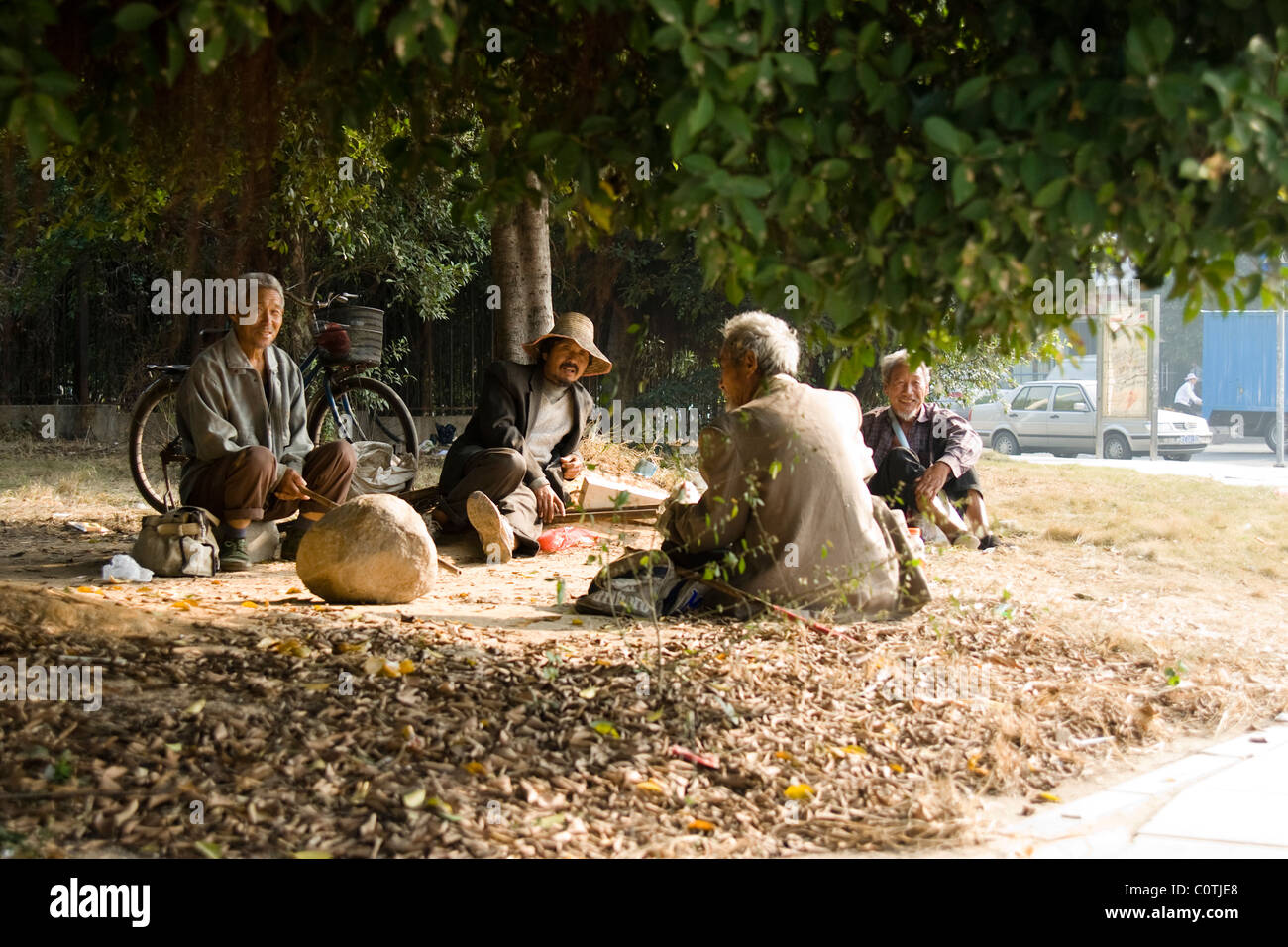 Chinese men sitting under a tree . Corner of the street in Dongguan, China Stock Photo