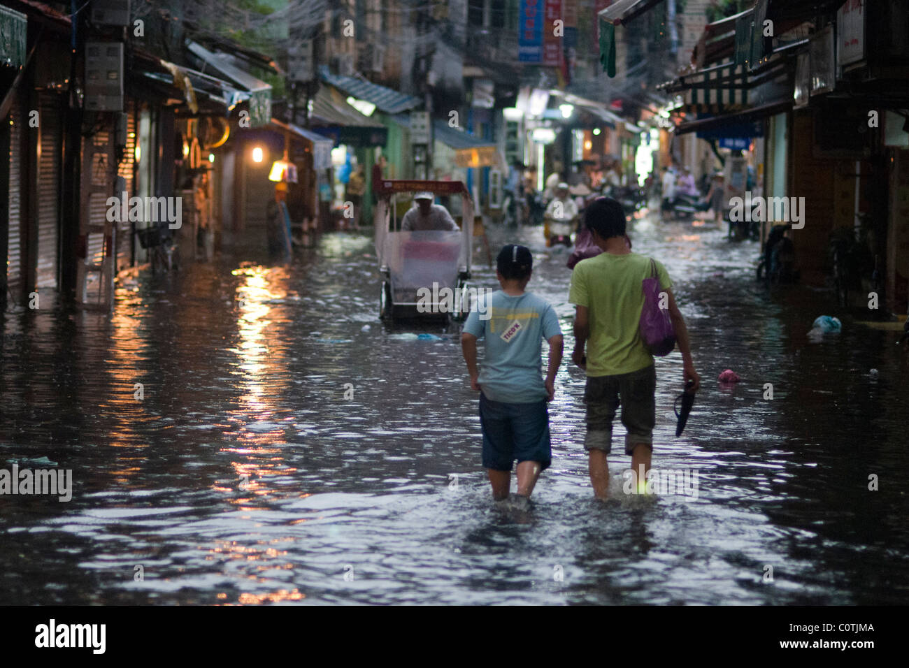 Two people walking through a flooded street in Hanoi Stock Photo - Alamy