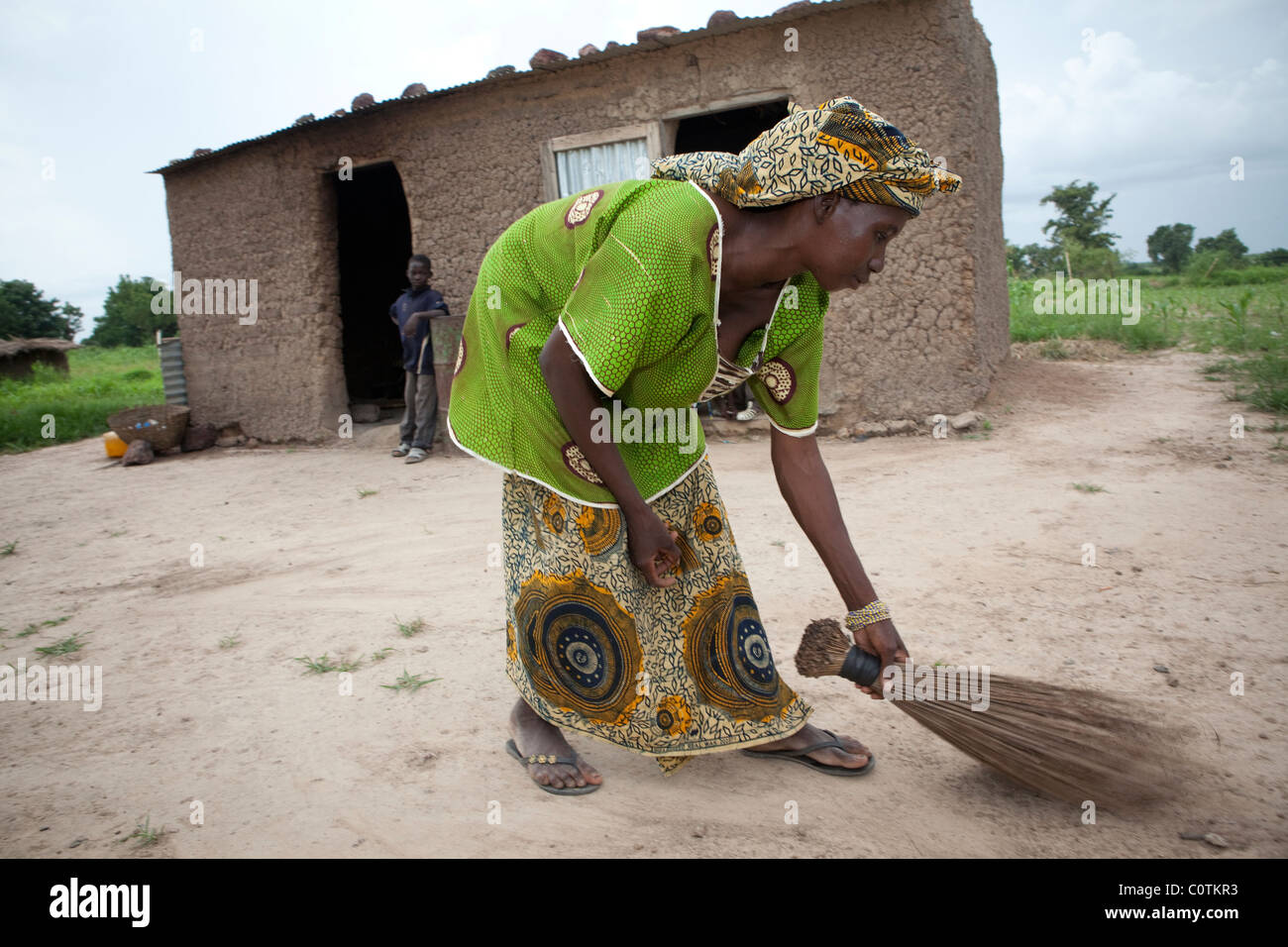 A young woman sweeps the family compound at her home in Safo, Mali
