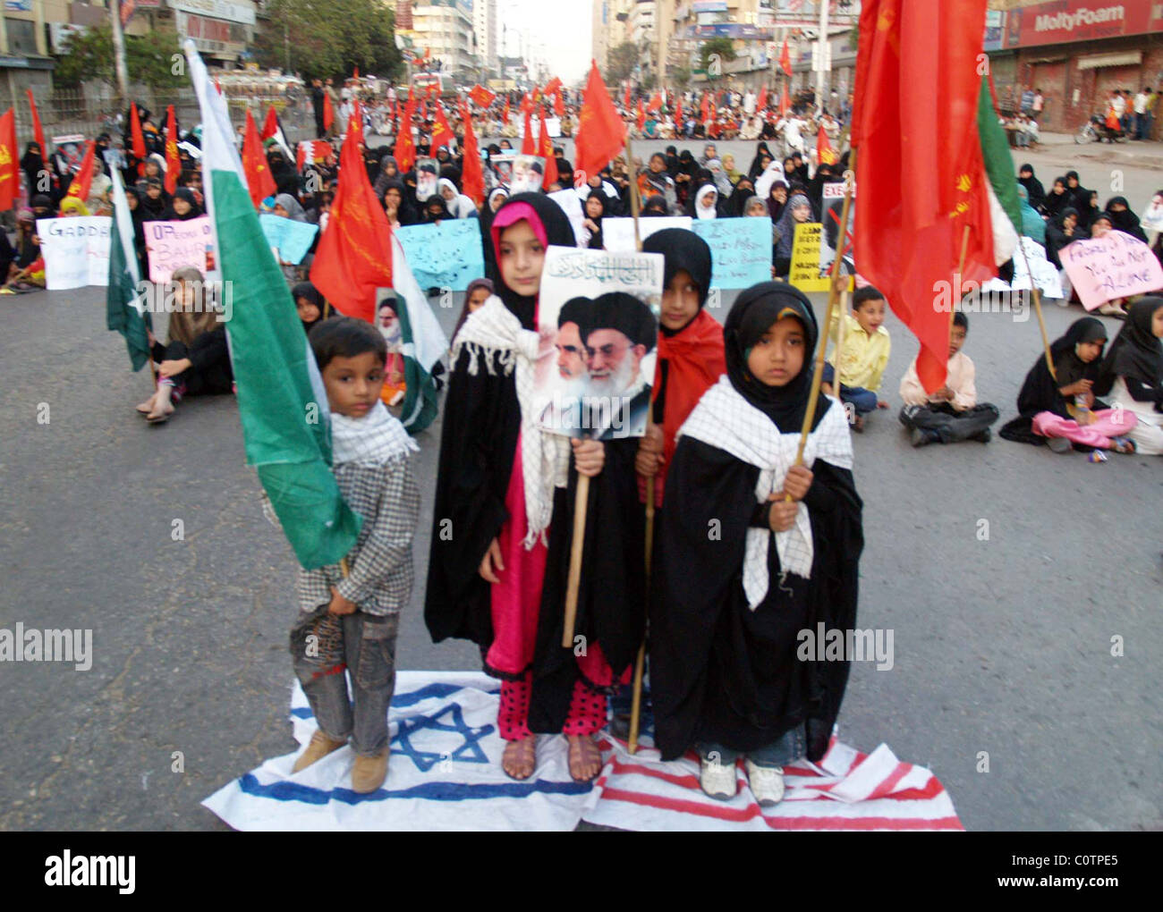 Children supporters of Majlis Wahdat-e-Muslimeen stand on US and Israel flags at MA.Jinnah road during “Difaye Muslimeen” Stock Photo