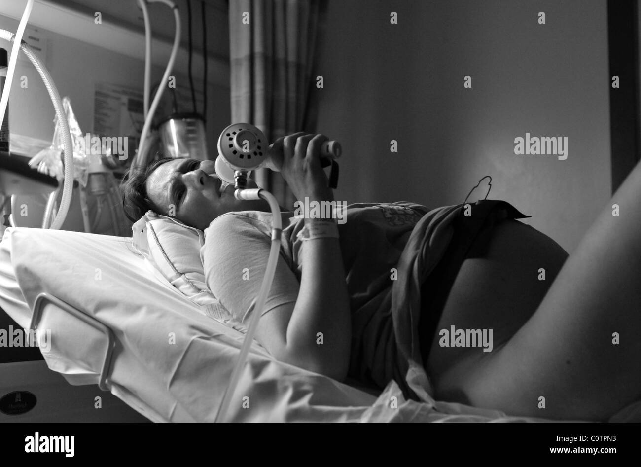 Pregnant woman in pain during labour taking gas and air mixture to relief pain Stock Photo