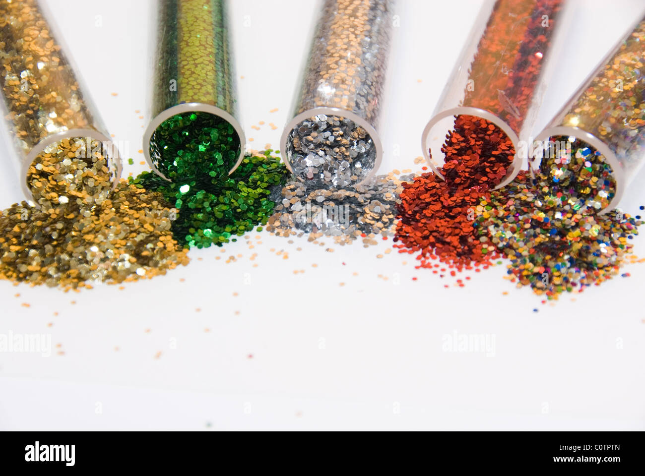 Colourful Sparkling Glitter Spilling Out Five Tubes Low Angle View Cut Out on White Stock Photo