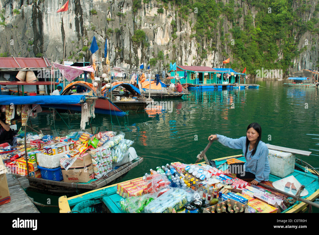 Karst  limestone rocks and Vietnamese people selling food to the tourists and their houses on the water Stock Photo