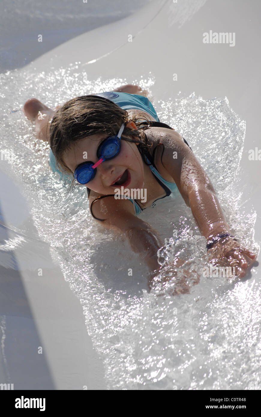 Little girl sliding head first down a water slide Stock Photo