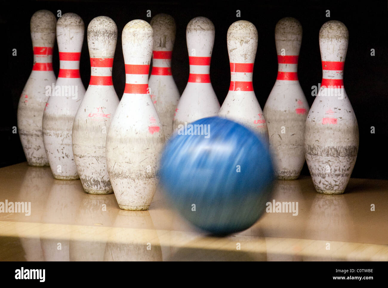 A bowling ball about to hit skittles in a tenPin bowling alley