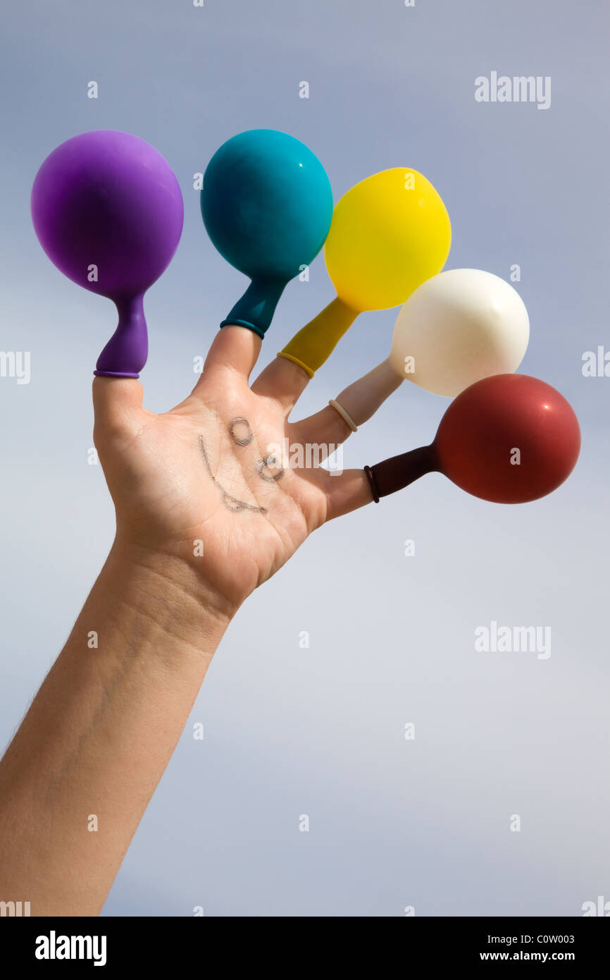 Face drawn on a hand with colored balloons on the fingers Stock Photo