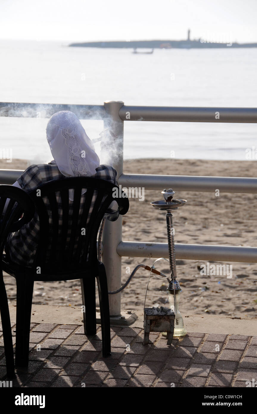 LEBANON MUSLIM WOMAN SMOKING A NARGILEH PIPE ON THE SEAFRONT IN SIDON