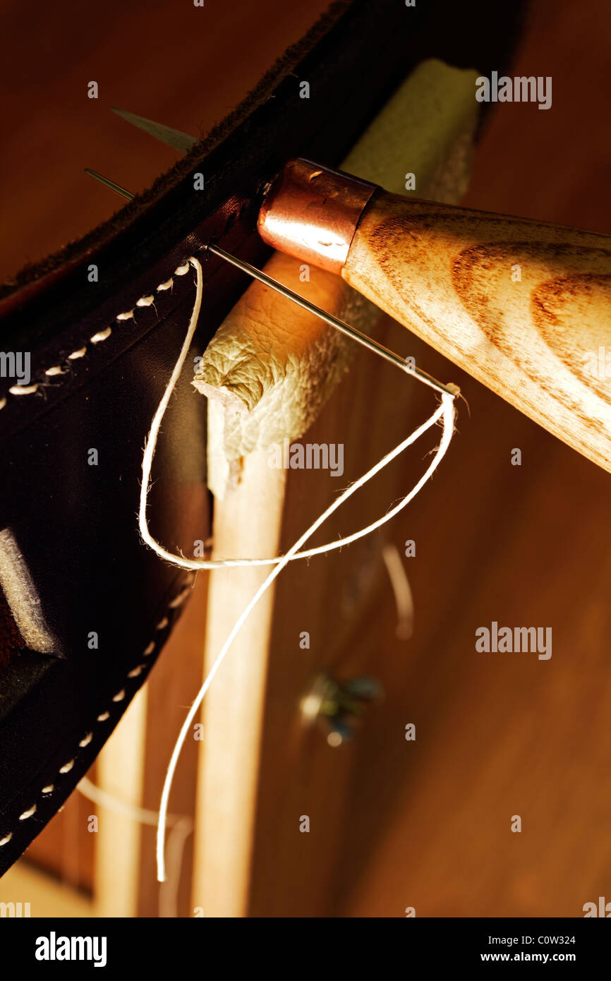 Hand stitching a leather belt using an Awl and stitching pony. Stock Photo