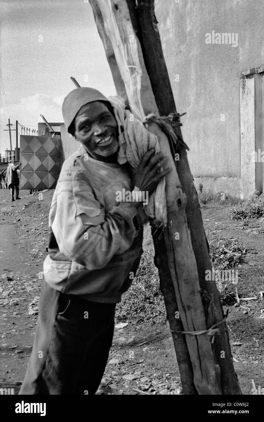 Burundian man carrying wood to the market, Ngozi, Burundi Stock Photo