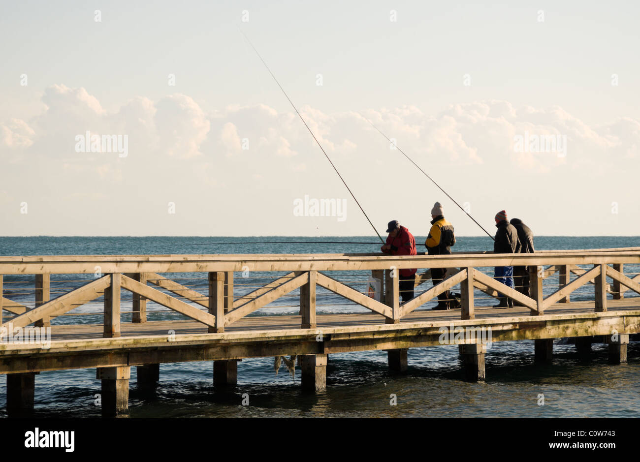 Ostia, Italy, four elderly men fishing from a pier, winter season Stock Photo