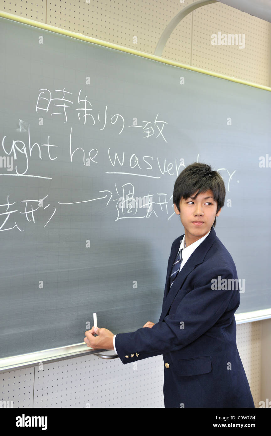 High School Boy Looking Back in front of Blackboard Stock Photo