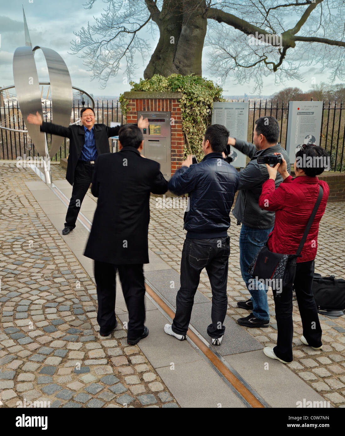 Tourists posing on the Greenwich Meridian line. Stock Photo