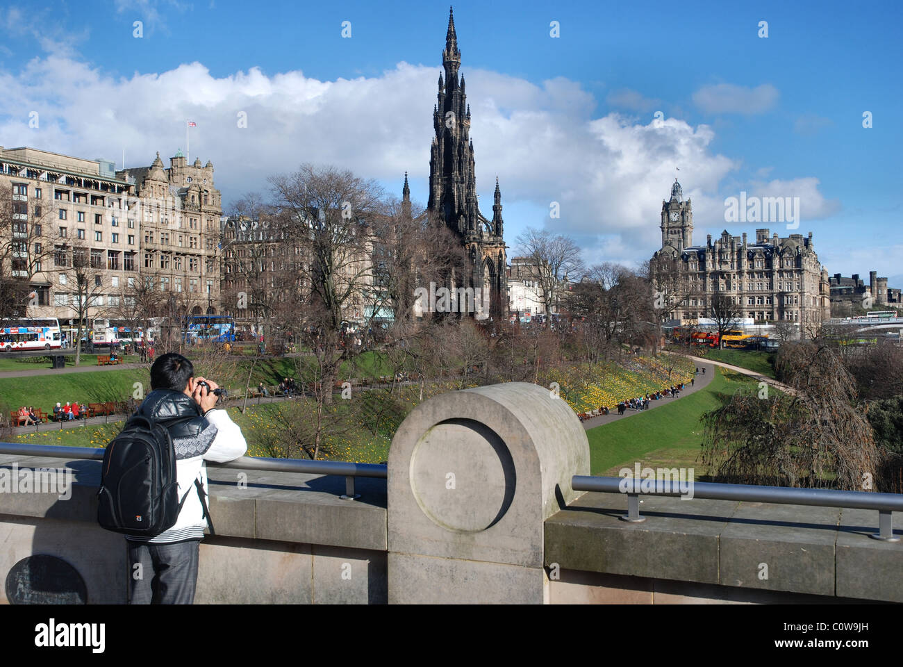 A tourist at The Mound in Edinburgh photographing Princes Street Gardens, the Scott Monument and Balmoral Hotel. Stock Photo