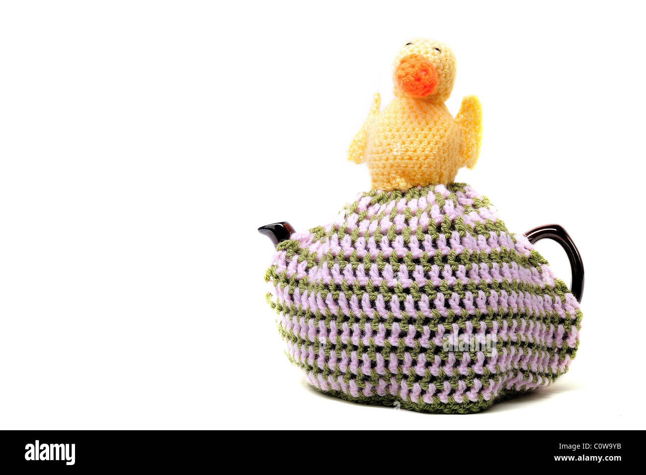Handmade crochet teacosy in green pink yellow and orange, sitting on top of a teapot Stock Photo