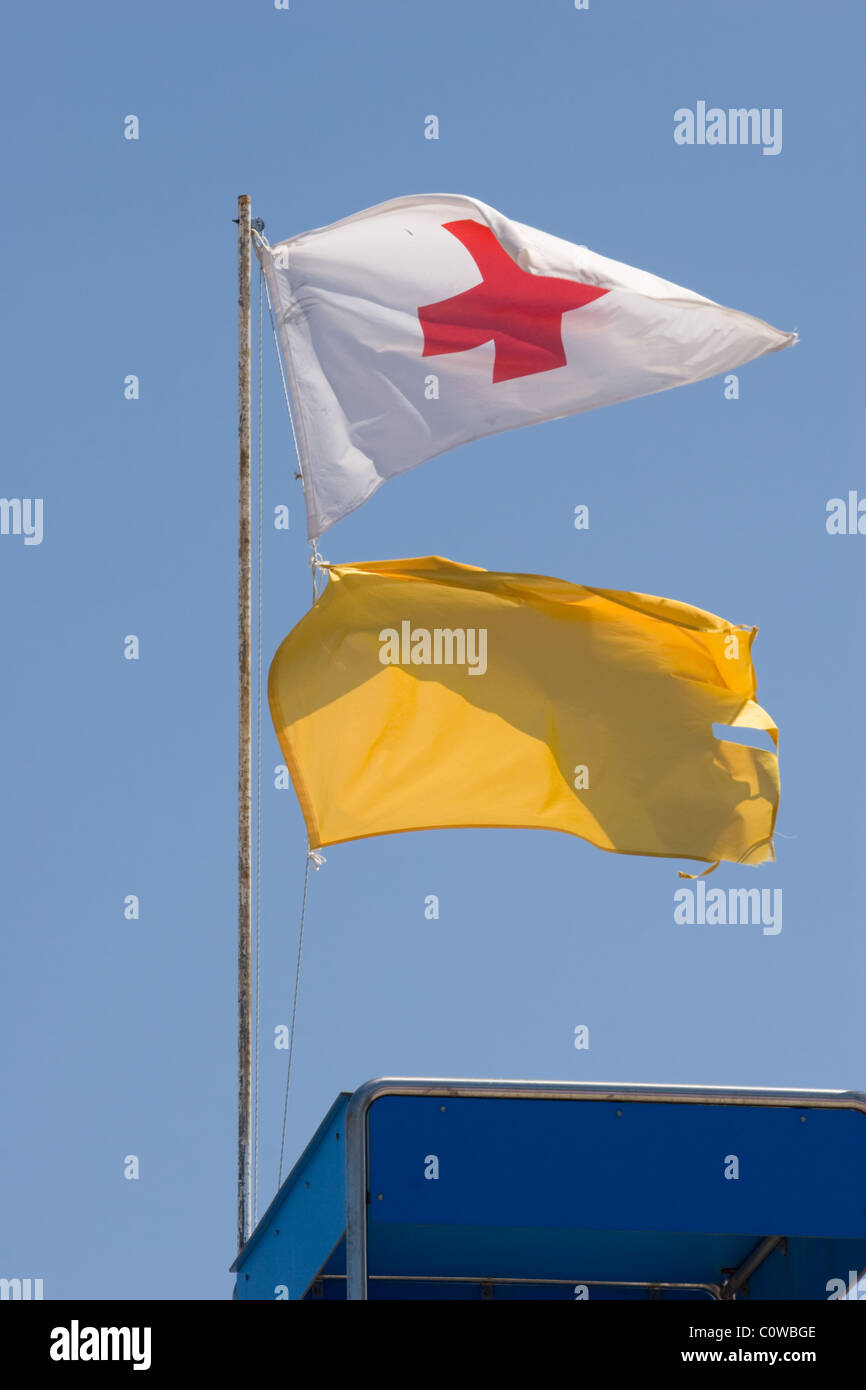 Red cross and yellow flags on a beach Stock Photo - Alamy