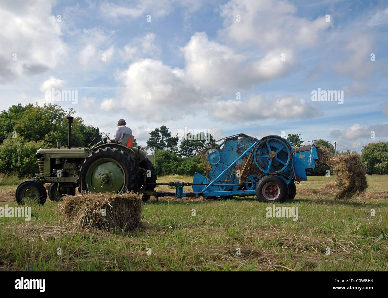 vintage tractor works on field with trussing machine Stock Photo