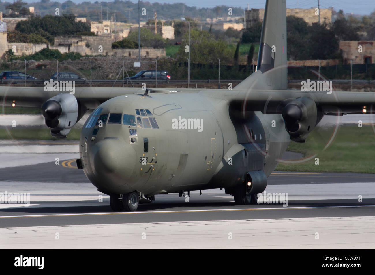 RAF Lockheed Martin C-130J Hercules military transport plane lining up on the runway for departure. Close up front view with emphasis on propellers. Stock Photo