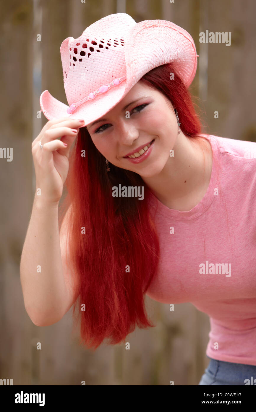 A young teenage girl with dyed red hair wearing a pink cowboy hat Stock Photo