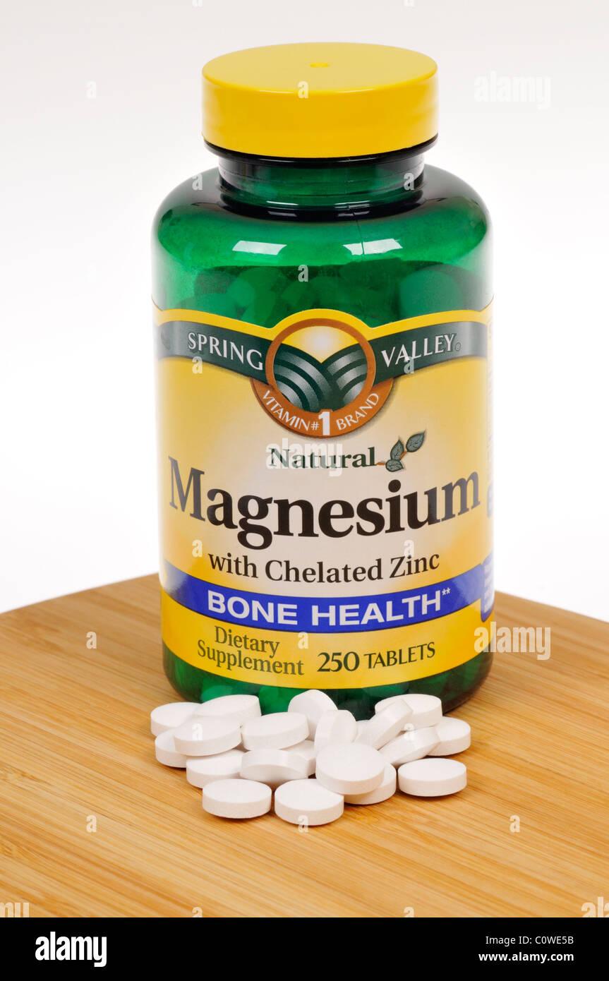 Bottle of Spring Valley Magnesium dietary supplement with tablets scattered. Stock Photo