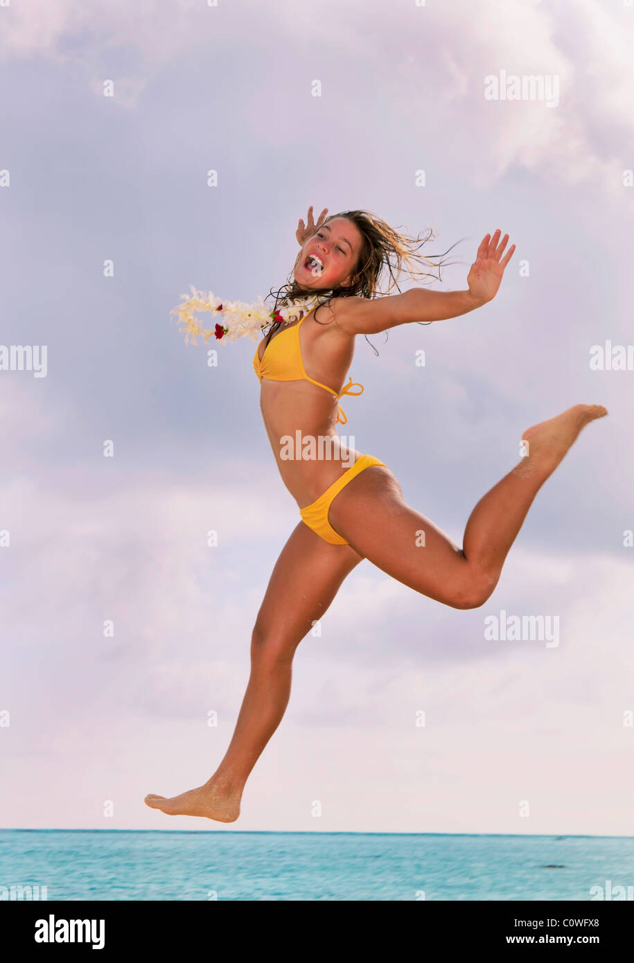 pretty girl in bikini with lei jumping at a hawaii beach Stock Photo - Alamy