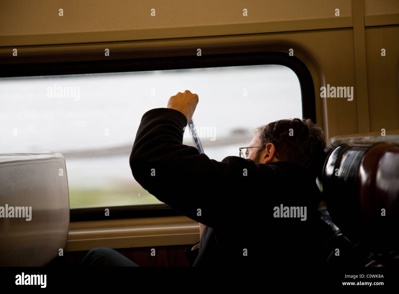 Man viewing negatvie film strip through window whilst sat on a train Stock Photo