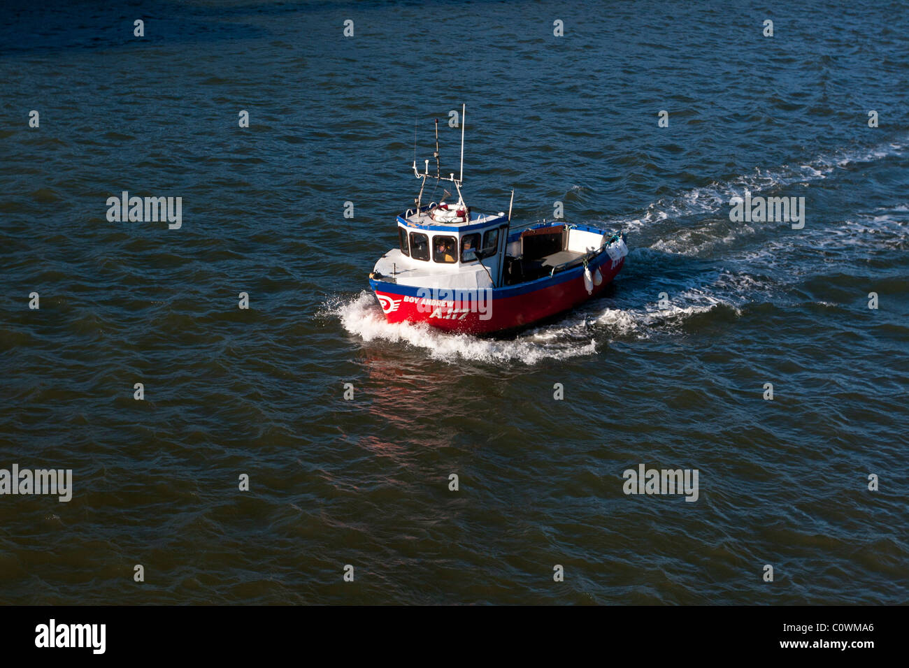 A red, blue and white fishing boat heads it to Whitby Harbor, North ...