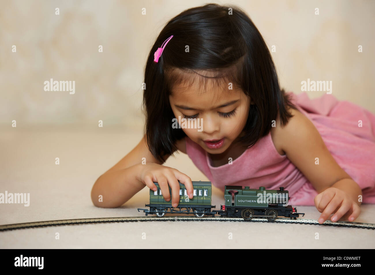 A young girl playing with her toy train set Stock Photo