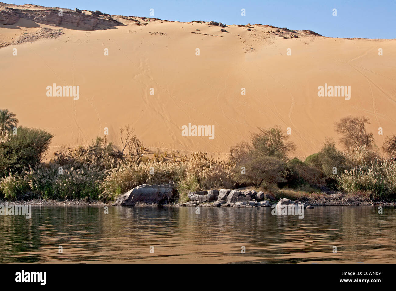 Desert sands sweep up to the edge of the Egypt's Nile River near Aswan. Stock Photo