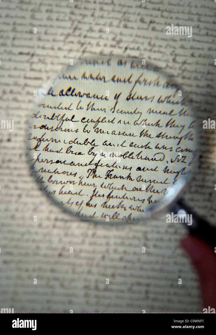 reading old manuscript through magnifying glass Stock Photo