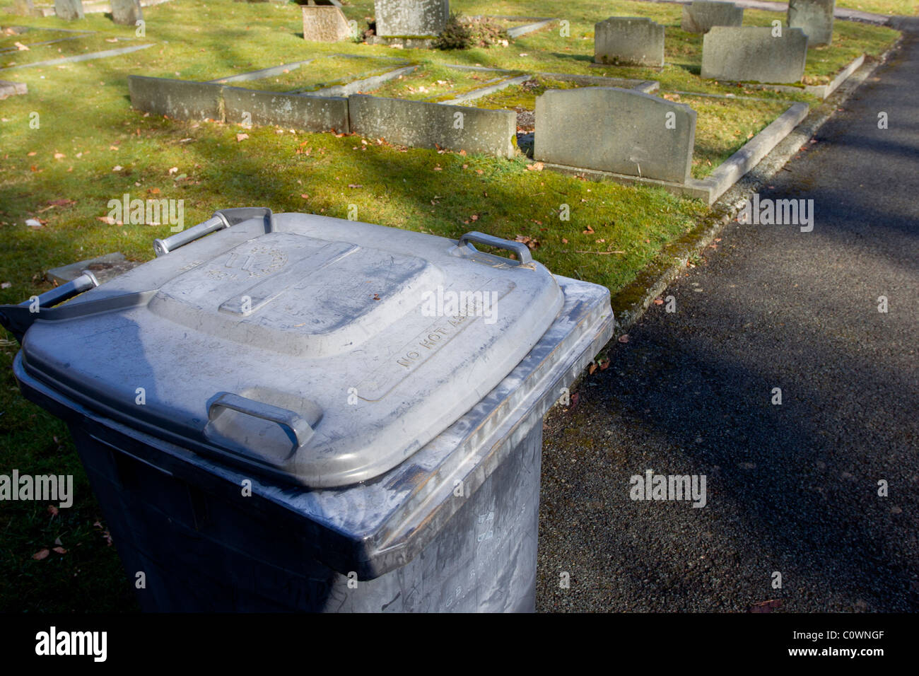 grave yard with head stones with Wheelie Bins say 'NO HOT ASHES Stock Photo