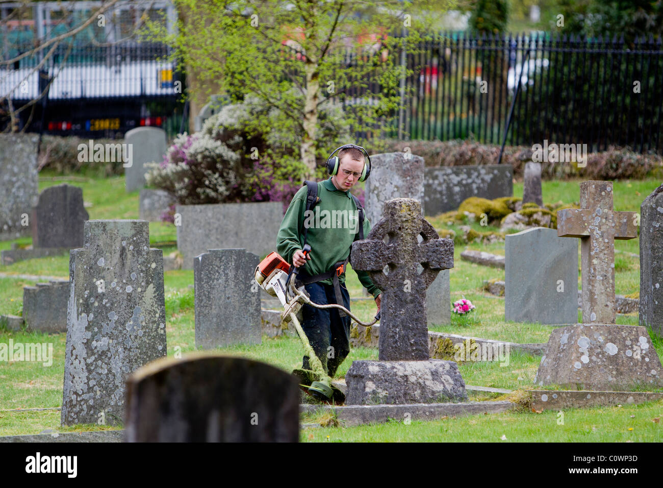 Strimmering cutting   the grass between the graves & grave stones Stock Photo