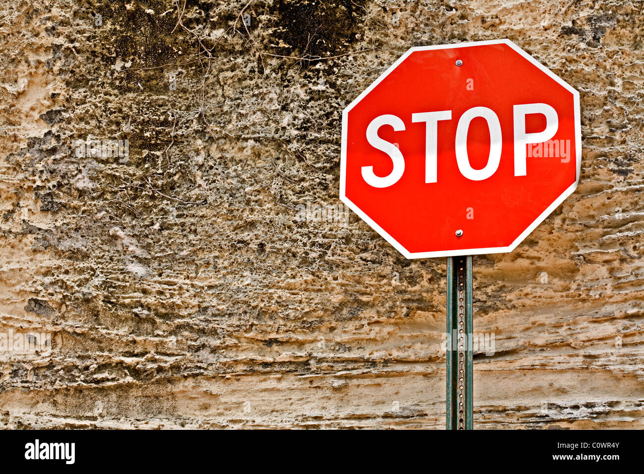 Stop sign in front of a weather-beaten wall. Stock Photo