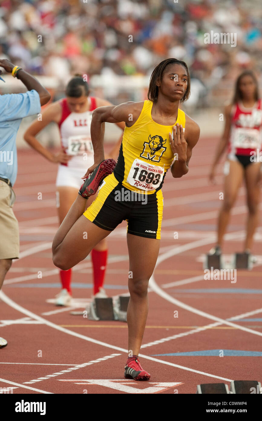 AfricanAmerican female track athlete stretches her leg before her race