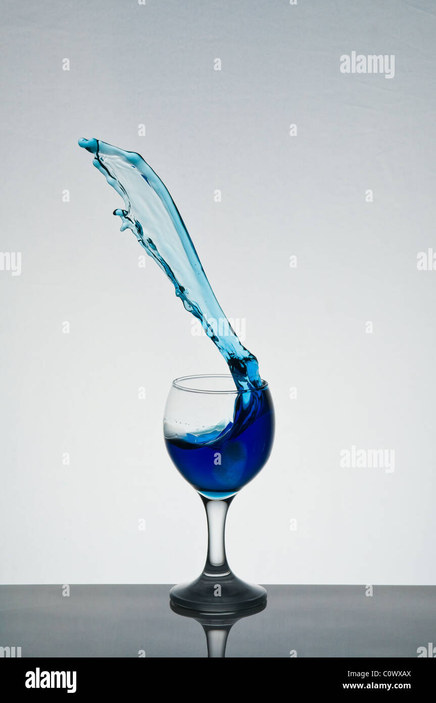 Colored liquid splashing out of a wine glass Stock Photo