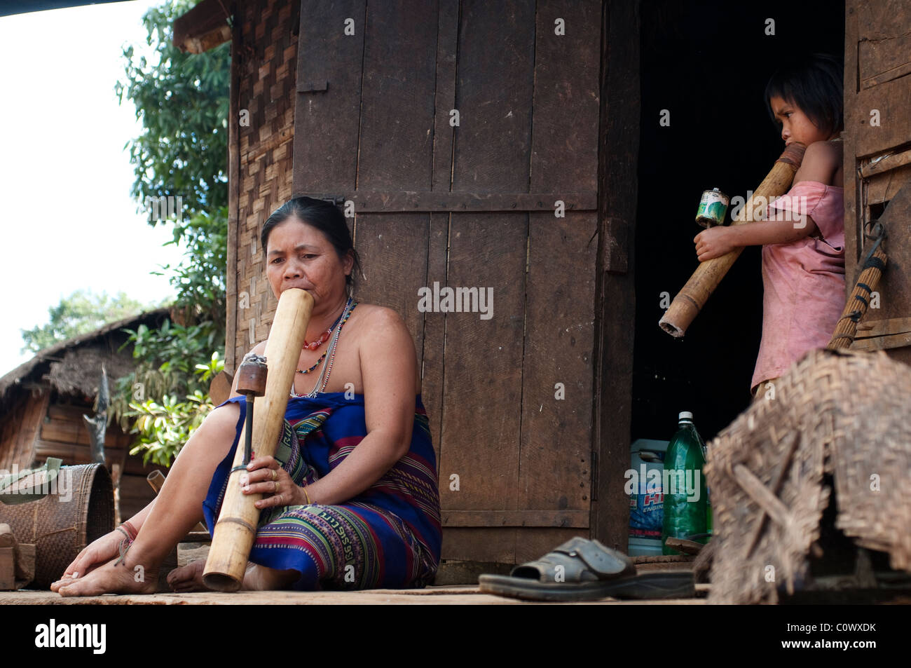 Woman and child smoking water pipes, Hill tribe village, Bolaven Plateau, near Pakxe, Laos Stock Photo