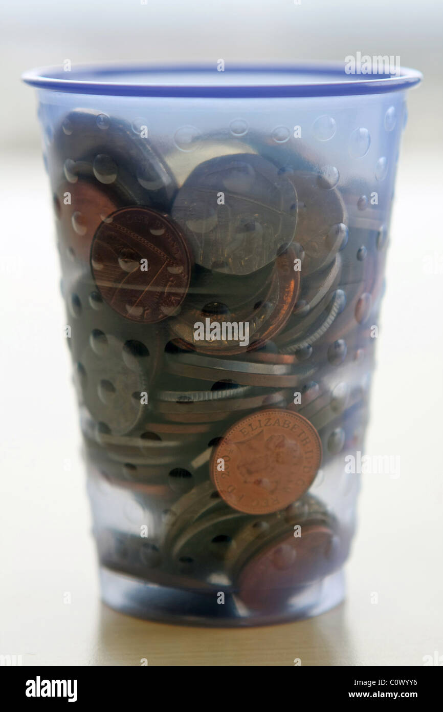 An eye level view of a plastic cup full of sterling coins Stock Photo