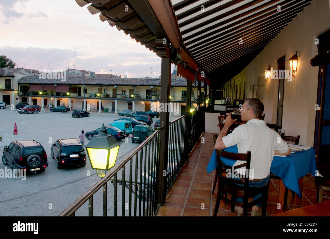 Man drinking a glass of wine and looking at the Main Square from a balcony. Colmenar de Oreja, Madrid province, Spain. Stock Photo
