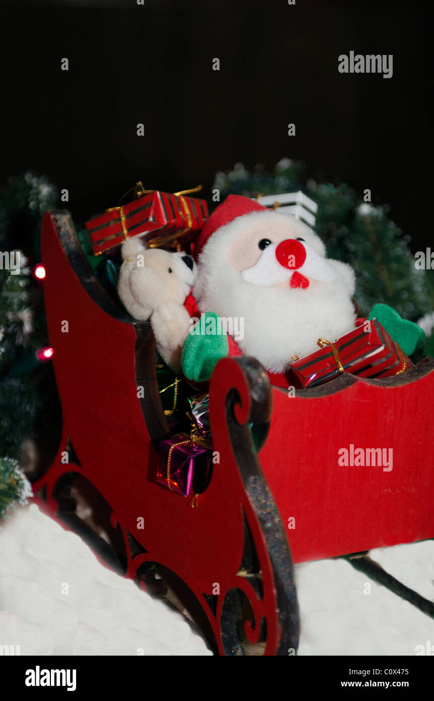 A Christmas decoration of Santa Claus in a wooden sleigh, with gifts. Stock Photo