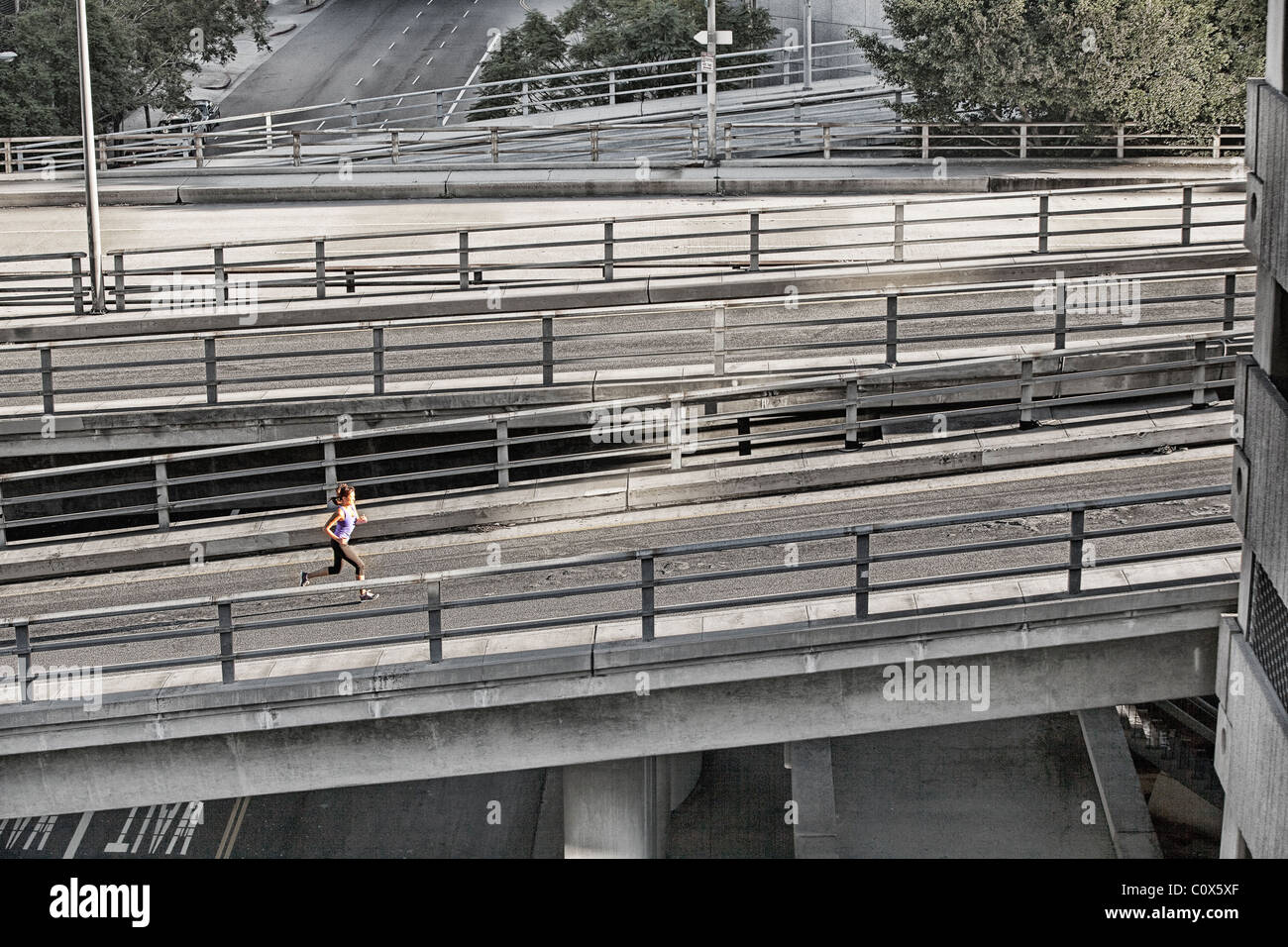 Female runner running on urban city street bridge, overpass in Los Angeles, California Stock Photo