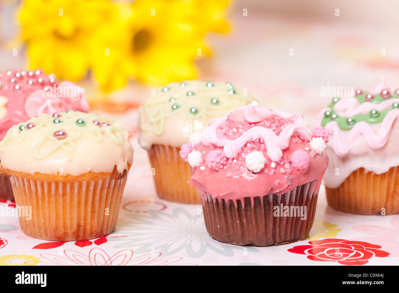 pink and yellow cup cakes on background with flowers. Stock Photo