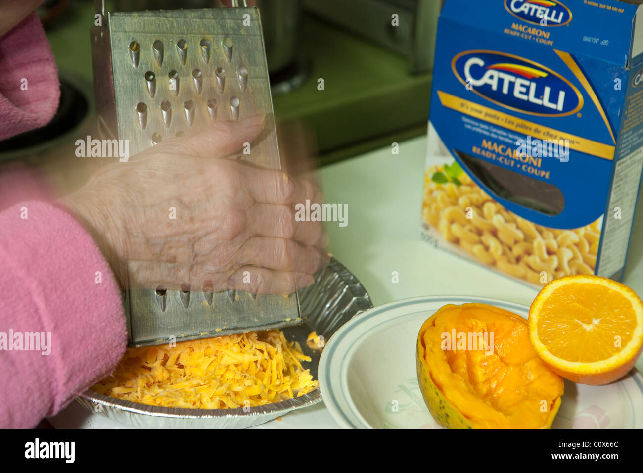 Elderly lady grating cheese for macaroni dinner-Victoria, British Columbia, Canada. Stock Photo